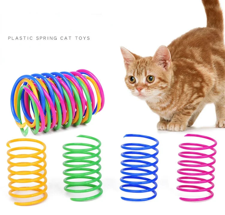 A collection of colorful spiral spring cat toys, including yellow, green, blue, and pink, next to an orange tabby cat.