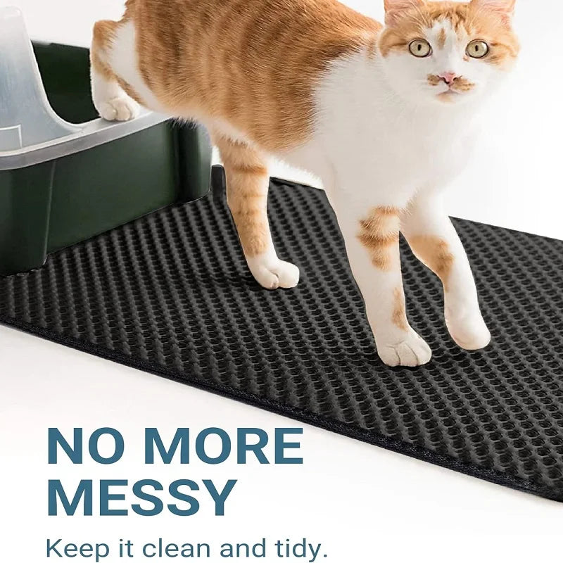 An orange and white cat is standing on a black, textured litter mat.
