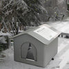 A gray foldable waterproof insulated cat house with a triangular window sits in a snowy outdoor setting.