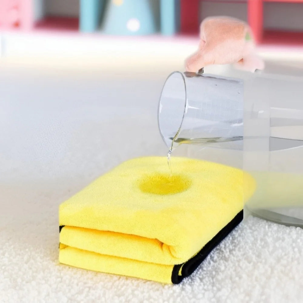Une serviette de bain pour animaux jaune ultra-absorbante qui goutte de l'eau dans un récipient en verre transparent.