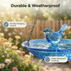 Blue glass bird bath fountain hanging from a chain with a small blue bird perched on the rim