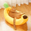 An orange tabby cat relaxing in a yellow banana-shaped plush pet bed.
