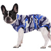 A black and white dog wearing a blue and gray camouflage recovery suit.