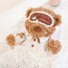 A fluffy brown teddy bear plush wearing a white collared shirt and pajamas with a 'Good Night' eye mask
