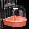 A clear plastic hanging bird bath with an orange base is suspended in a wire cage.
