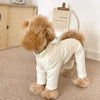 A light beige soft stretch dog pajama jumpsuit for a small to medium pet standing on a carpet.