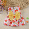 Robe d'été à motifs de fraise jaune et rose avec un grand nœud jaune posé sur un tapis tissé.
