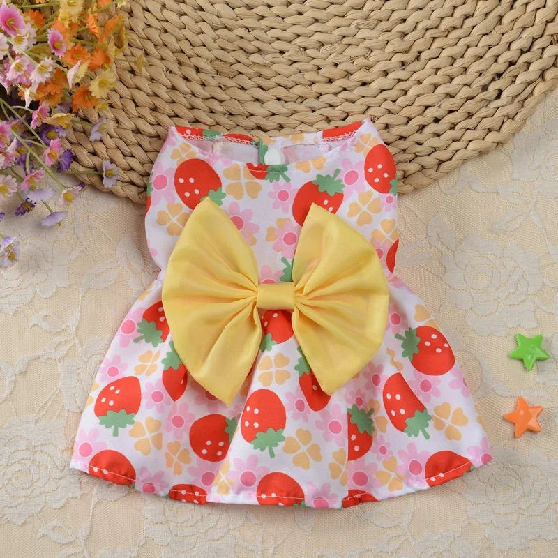 Robe d'été à motifs de fraise jaune et rose avec un grand nœud jaune posé sur un tapis tissé.