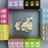 A collection of handcrafted mini house-shaped bags in various colors, including pink, black, blue, and yellow, with puppy key
