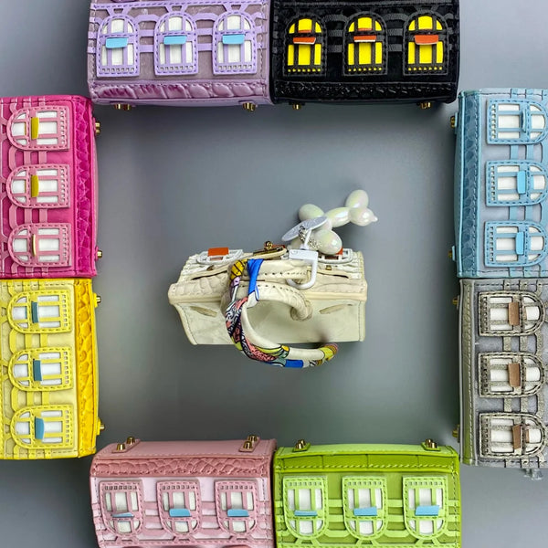 A collection of handcrafted mini house-shaped bags in various colors, including pink, black, blue, and yellow, with puppy key