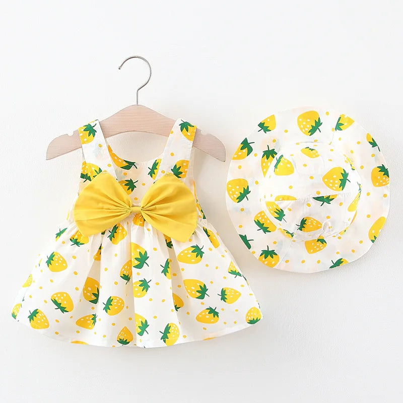 Gelbes und weißes Erdbeermuster-Sommerkleid und passende Mütze für Mädchen auf einem Hänger.