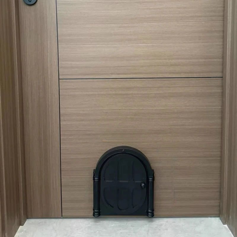 A dark black pet door is installed in a light brown wood panel, set into a modern door frame.