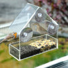 Nourrice pour oiseaux en verre avec ventouses, contient graines et eau.