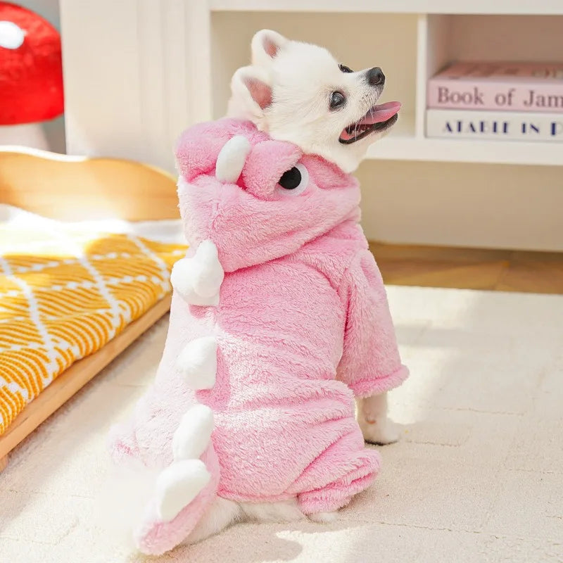 A pink cozy fleece dog hoodie with animal ears lying on a light-colored floor.