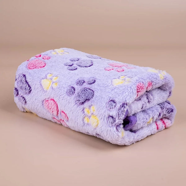 A soft pet fleece blanket featuring a purple background with pink, yellow, and purple paw print designs.
