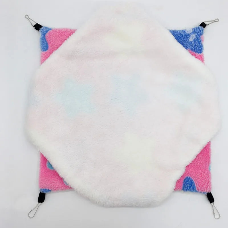 A white fleece hammock bed with pink and blue accents for a hamster.