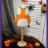 Disfraces de calabaza naranja ajustable para Halloween mostrados en un maniquí blanco junto a calabazas talladas pequeñas.