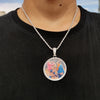 A silver chain necklace features a round pendant depicting a photo of people.