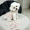A fluffy white dog wearing a pink floral princess style anti-shedding dress.