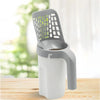 A gray heavy duty cat litter shovel with a mesh top and a white plastic refill bag is shown on a wooden surface.