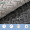 Close-up of a gray quilted pet mat showing water droplets on the surface and icons for low temperature iron, no bleach, tumbl