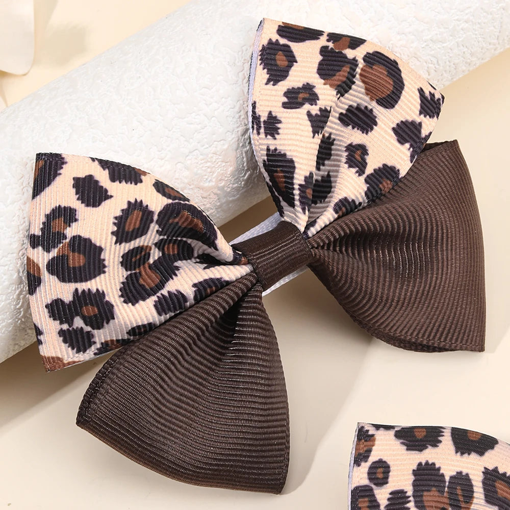 Eine Paar Leopardenmuster-Haarspangen in Beige- und Brauntönen neben einem weißen Handtuch.