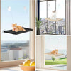 A fluffy orange cat is relaxing on a hanging window perch with suction cups, viewed through a window.