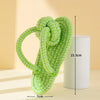 A bright lime green rope ball dog toy made of yarn, shown next to a cylindrical object.