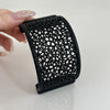 A black 3D printed floating betta hammock for aquarium decor is held by a hand.