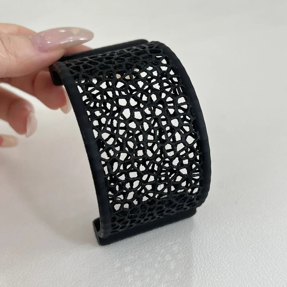 A black 3D printed floating betta hammock for aquarium decor is held by a hand.