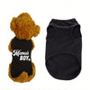 A fluffy golden dog toy wearing a black vest with white text that reads Mama's Boy.