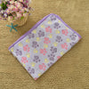 A purple fleece pet bed mat cover with paw prints in pink, yellow, and gray on a beige textured surface.