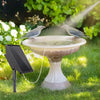 Une pompe aérateur de bassin alimentée par énergie solaire arrose un bain d'oiseaux dans un jardin ensoleillé.