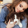 A woman holds a puppy with an LED training collar, demonstrating the product for dog training.