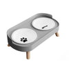 A gray stainless steel double bowl for dogs and cats with two white ceramic bowls and a wooden stand.