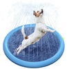 A white dog is jumping in a blue inflatable splash pad, creating water spray.