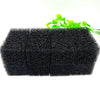 Two rectangular blocks of black aquarium bio sponge filter media with green plant leaves in the background