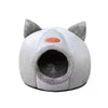 A round gray plush cat cave bed with pointed ears and an oval entrance.