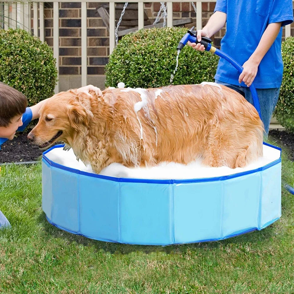 Una persona está llenando una piscina inflable azul de espuma para perros y gatos en el patio trasero.
