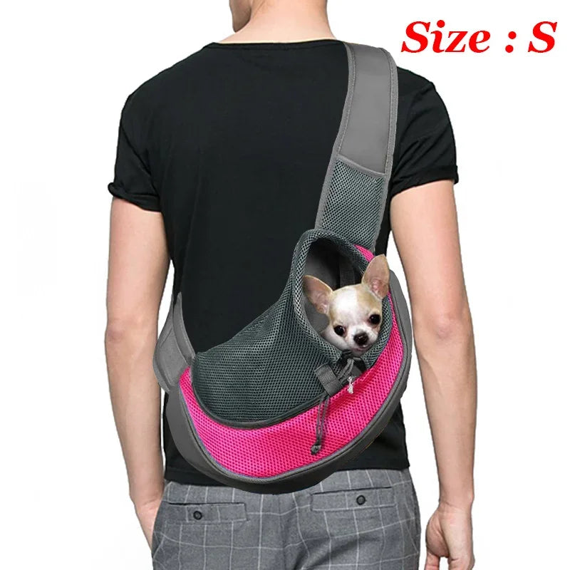 A person is wearing a gray breathable dog sling carrier with a pink lining and a small dog head visible inside.