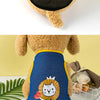 A fluffy yellow dog wearing a blue mesh summer vest with a cartoon lion print.
