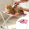A cat is being bathed using a portable pet grooming hammock stand with a handheld device.