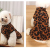 A fluffy white dog wearing a leopard print princess dress on its back.