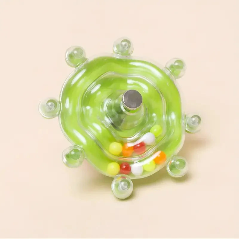 Grüner, rotierender Spielzeugspender mit kleinen bunten Leckereien auf der Oberfläche.