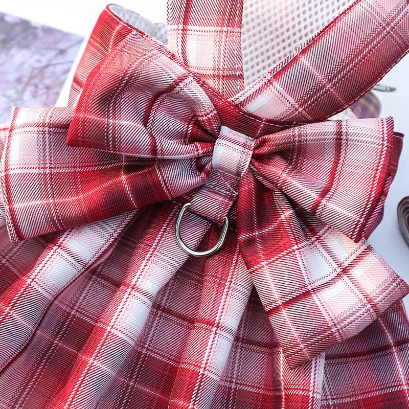 A red and white plaid bow made of fabric is shown, likely part of a dog dress-up harness or clothing.