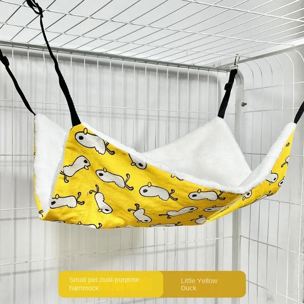 A yellow duck-themed pet hammock is hanging inside a wire cage.