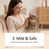 A woman gently pets a tabby cat while holding a bottle of mild and safe cat deterrent spray.