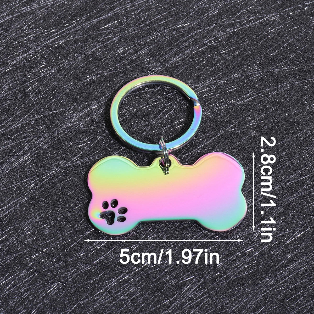 A shiny, iridescent bone-shaped dog ID tag with a metal ring attached, displayed on a dark surface.