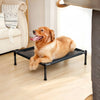 A golden retriever dog is relaxing on a black portable folding pet bed indoors.