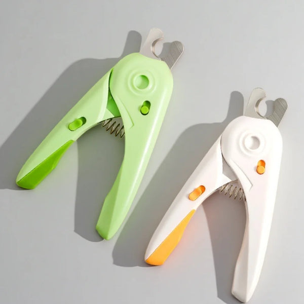 A pair of light green and white safety guard pet nail clippers lying on a gray surface.